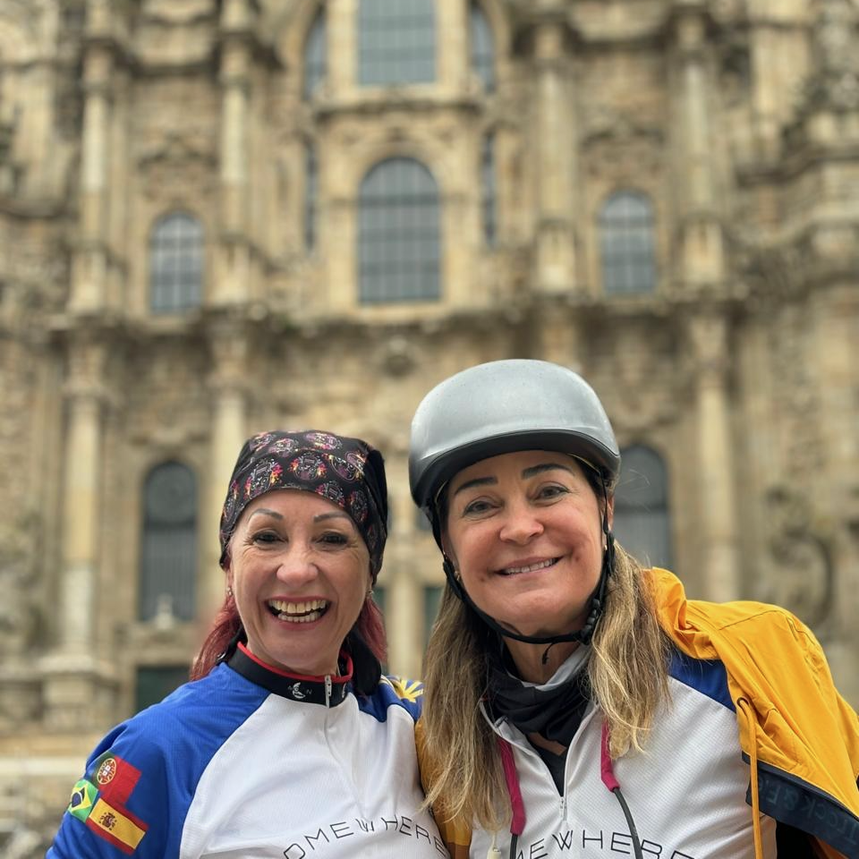 Two smiling cyclists in front of Santiago Cathedral