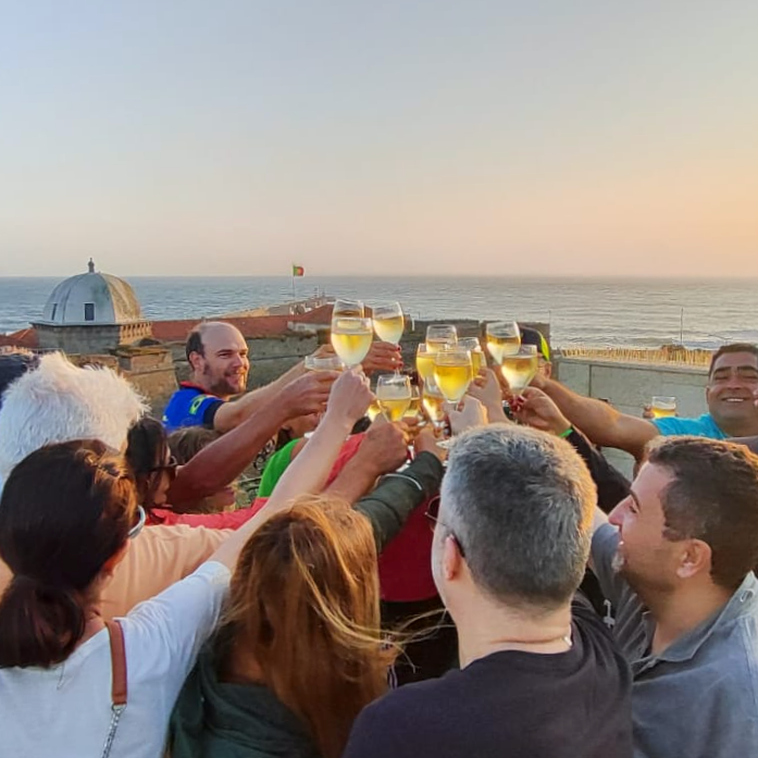 Tour group raising glasses in a sunset toast by the Atlantic