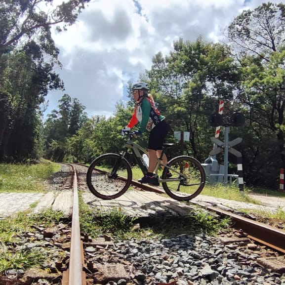 Cyclist crossing railway tracks on a wooded Camino trail