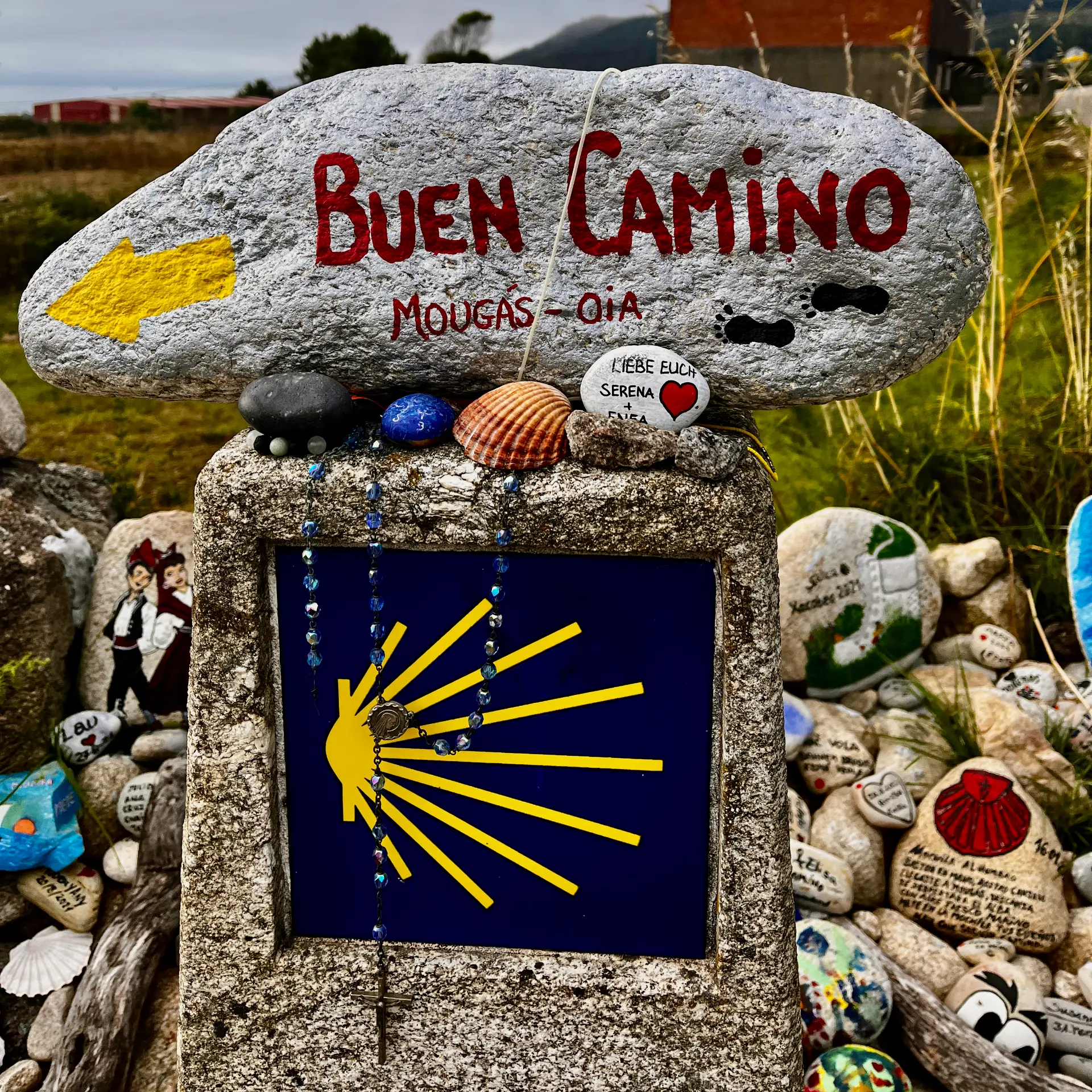 Buen Camino stone marker decorated with shells and pilgrim keepsakes