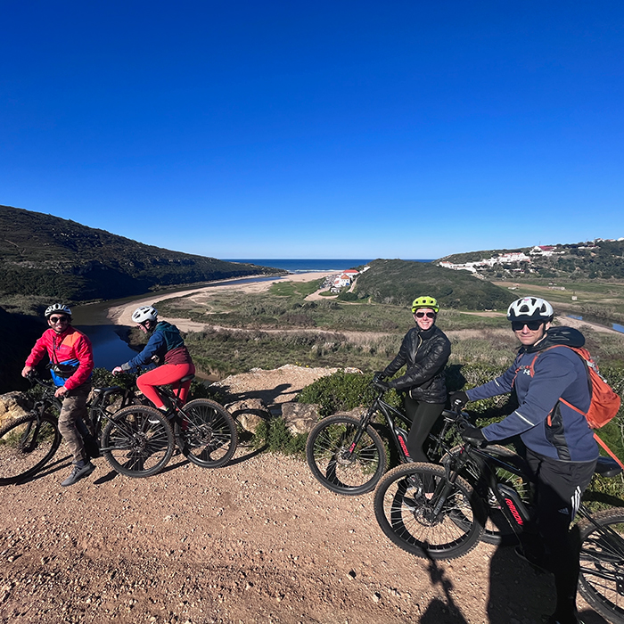 Cyclists pausing on a hill with the Atlantic coast in the distance
